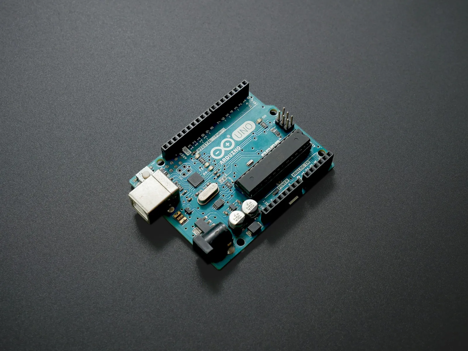An Arduino Uno board on a dark surface